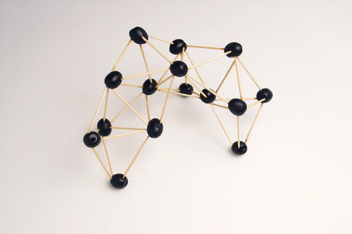 Black olives connected by wooden cocktail sticks representing an atomic molecule.
